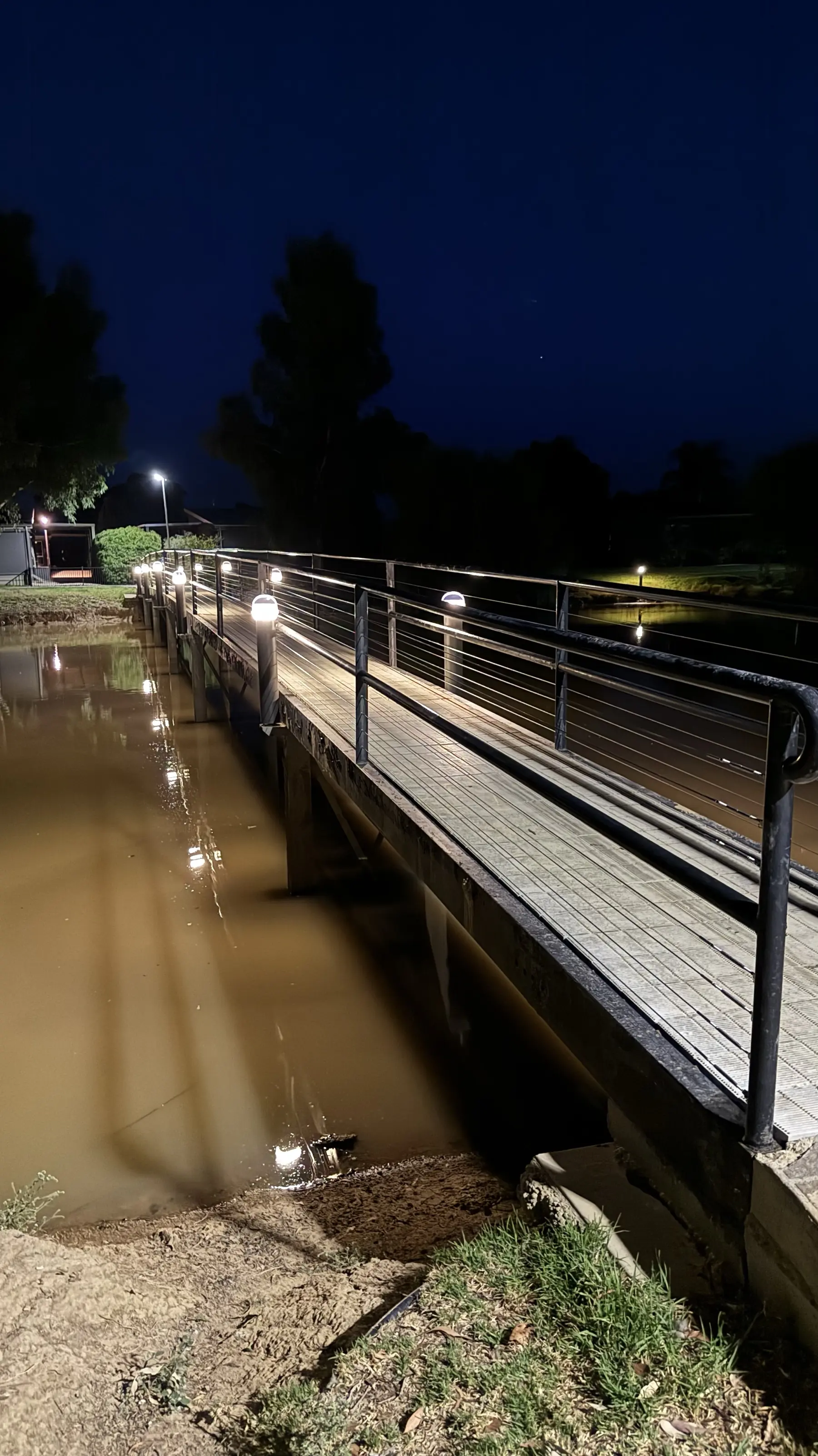 Solar bollards lighting a footbridge over the water at night at Discovery Parks Moama Waters
